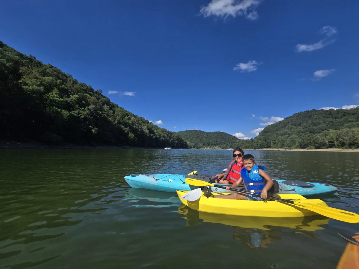 Two kayakers paddling on the Youghiogheny between green mountains